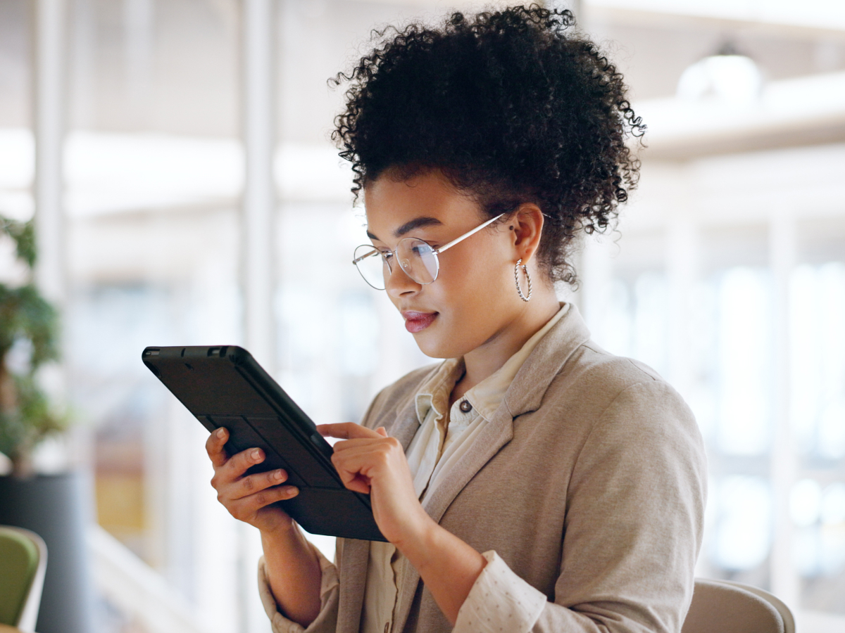 Woman with glasses using a tablet in an office setting