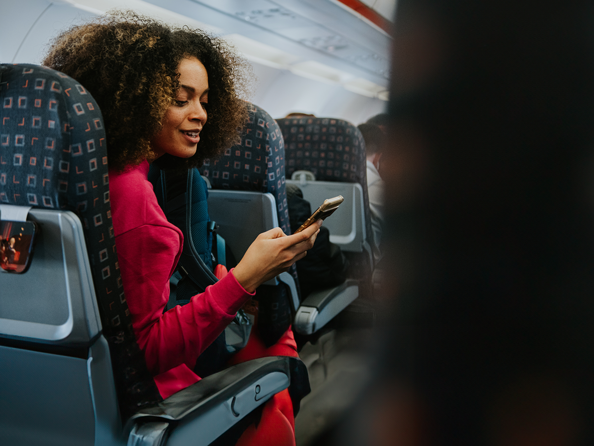 A woman sitting on an airplane, focused on her phone while enjoying her flight