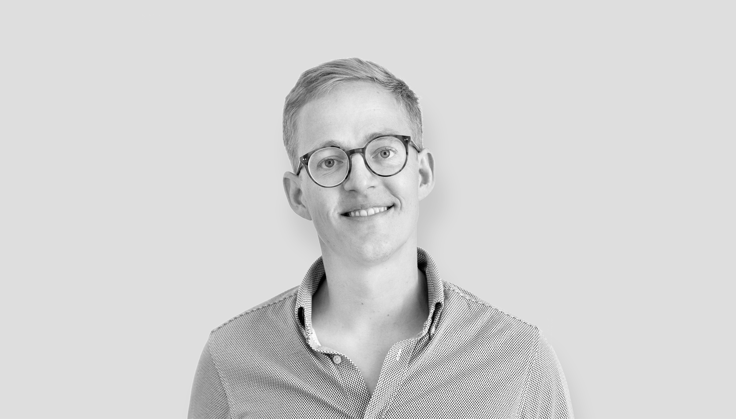 A smiling man wearing glasses and a shirt, exuding a friendly and approachable vibe.  