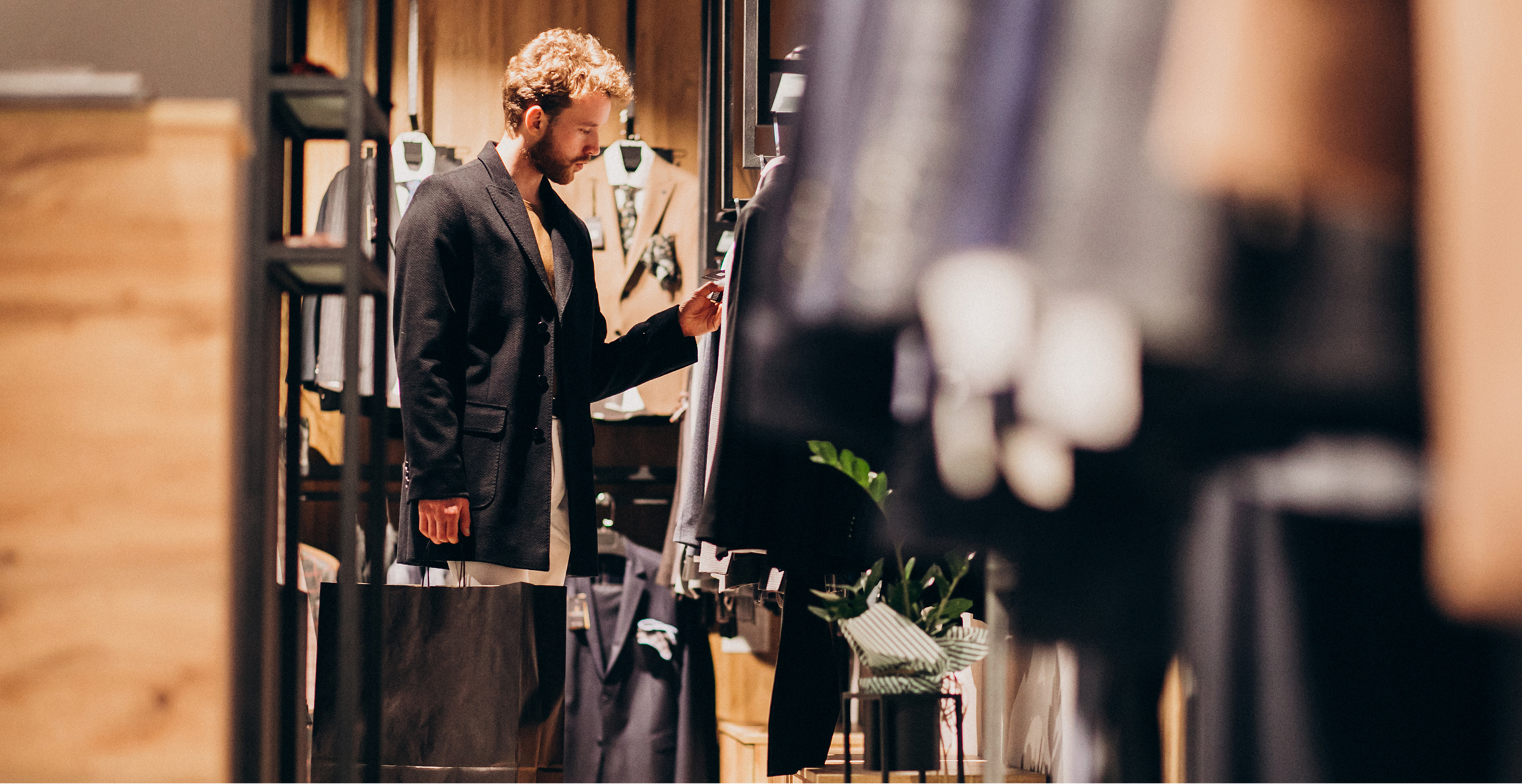 A man examines clothing options while browsing in a clothing store. 