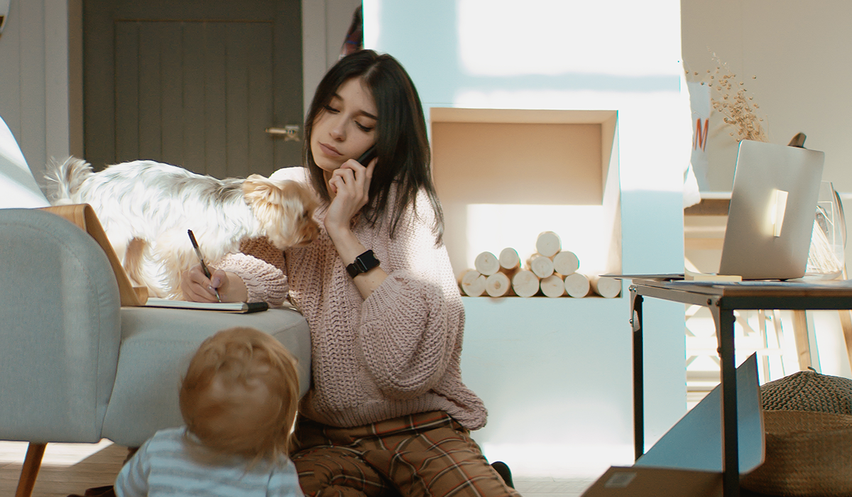 Woman working remotely while watching her toddler.