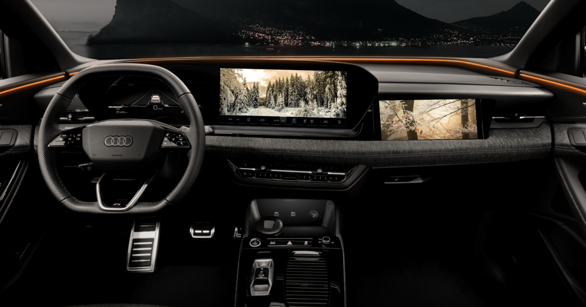 Interior view of a luxury Audi vehicle showcasing a sleek, high-tech dashboard. The digital display features multiple screens, including navigation with a snow-covered forest scene and a right-side monitor displaying a scenic image. Ambient lighting adds an orange glow, complementing the modern, minimalistic design. The background reveals a serene night landscape with a lake and mountains visible through the windshield.