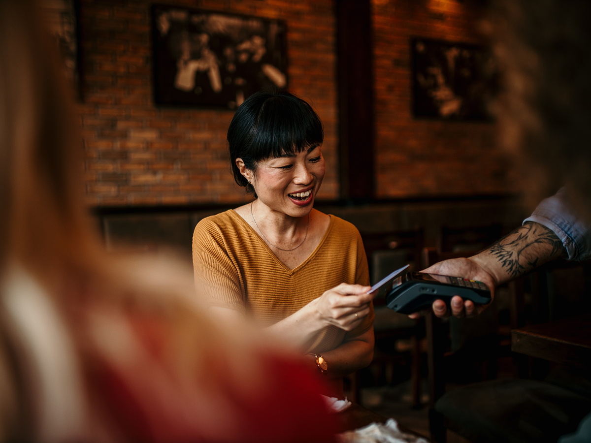 A woman smiles while holding a phone, looking cheerful and engaged