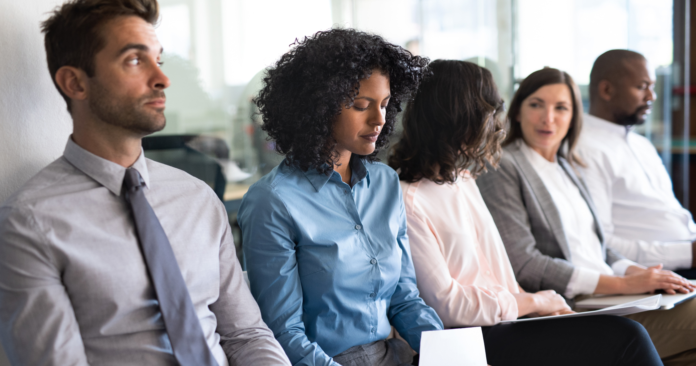 A group of five people sitting in a row as if waiting for something.