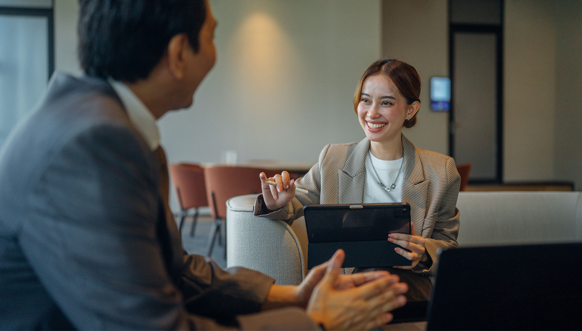 A man and woman in business attire engaged in a conversation in a professional setting