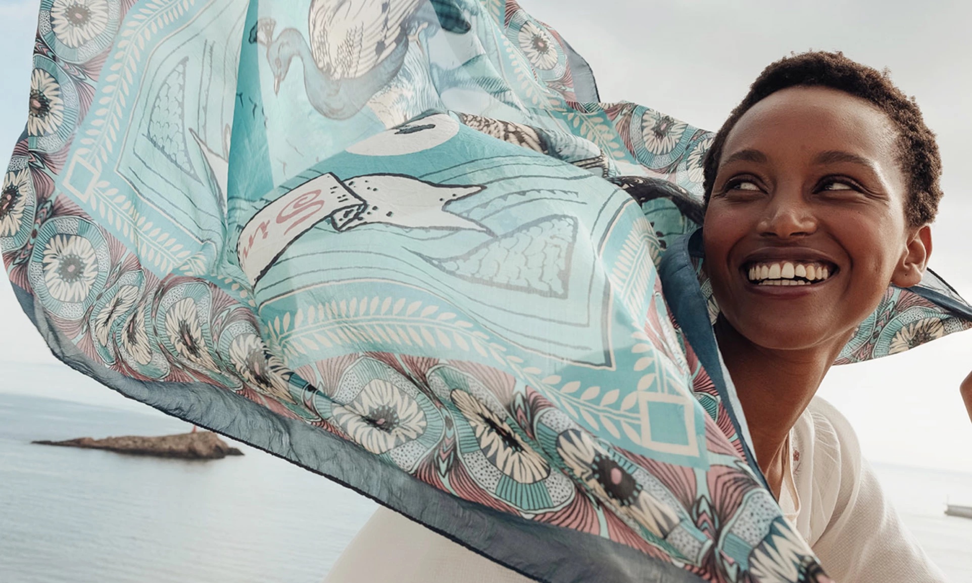 Woman smiling with green scarf blowing in the wind
