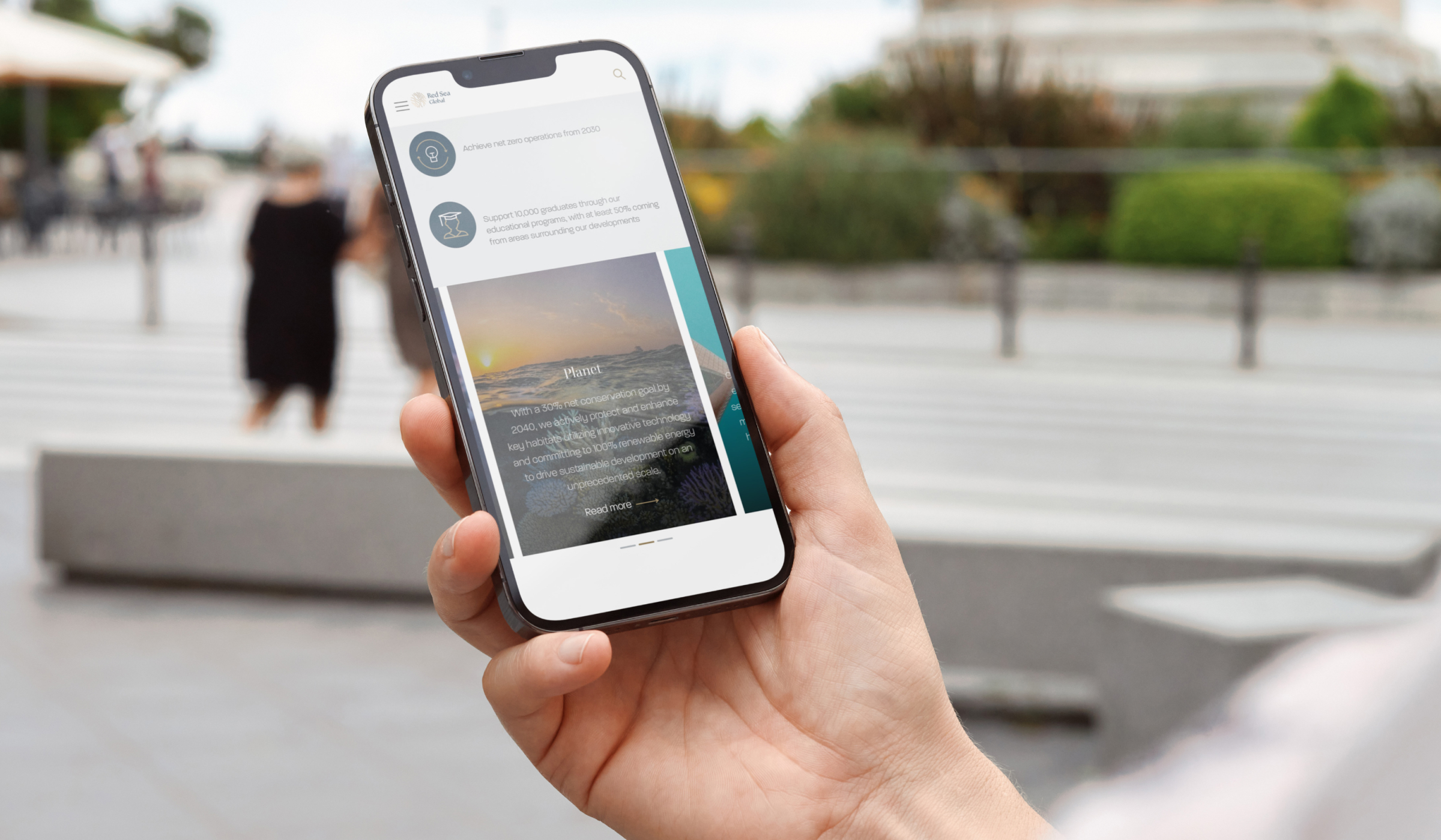A hand holding a smartphone displaying the "Red Sea Global" website