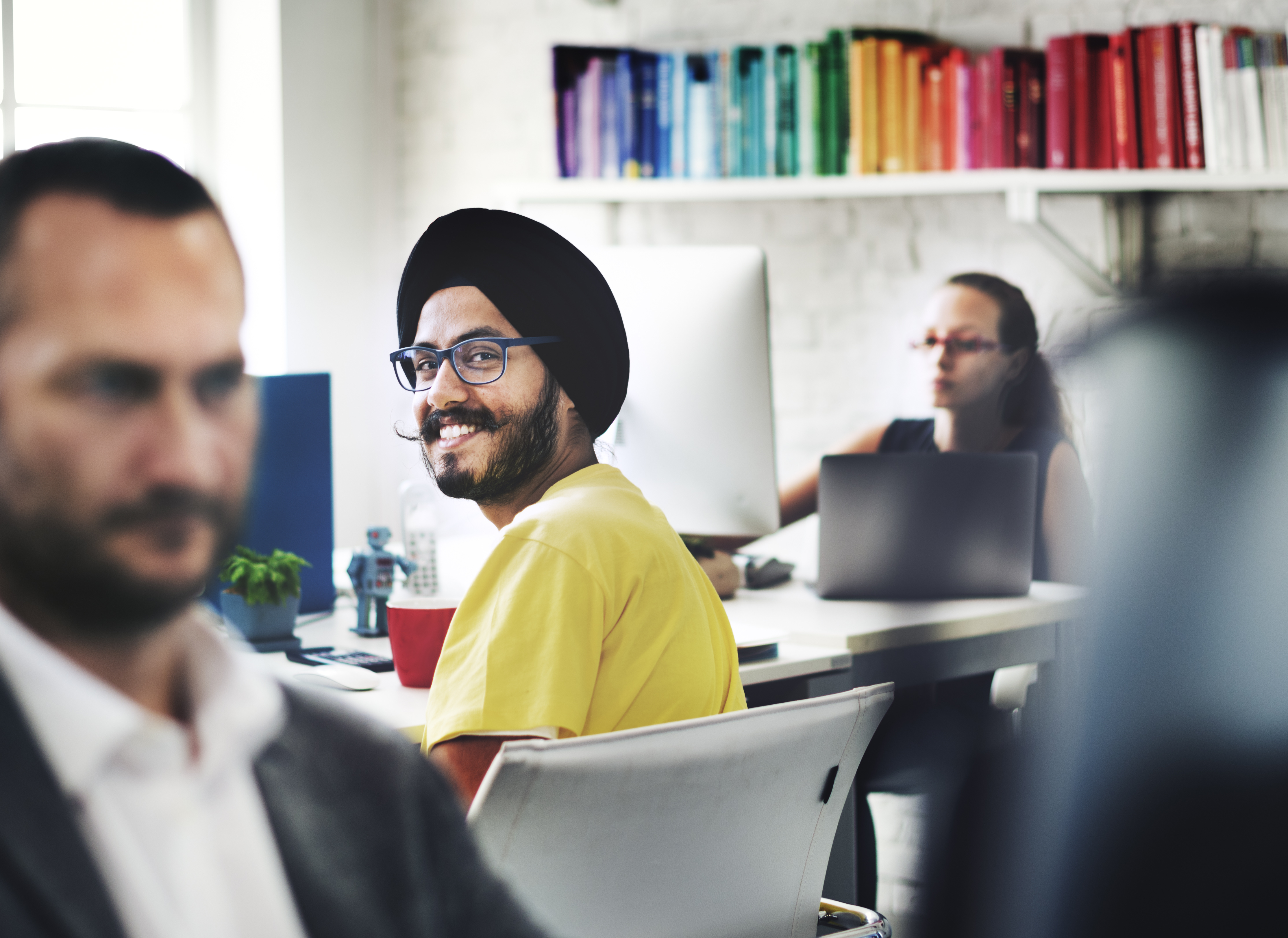 A man in a yellow jumper smiles at the camera
