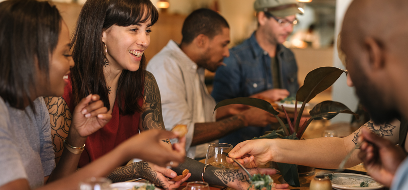 Group of friends sharing food and enjoying conversation at a trendy restaurant, highlighting modern dining experiences and social food culture.
