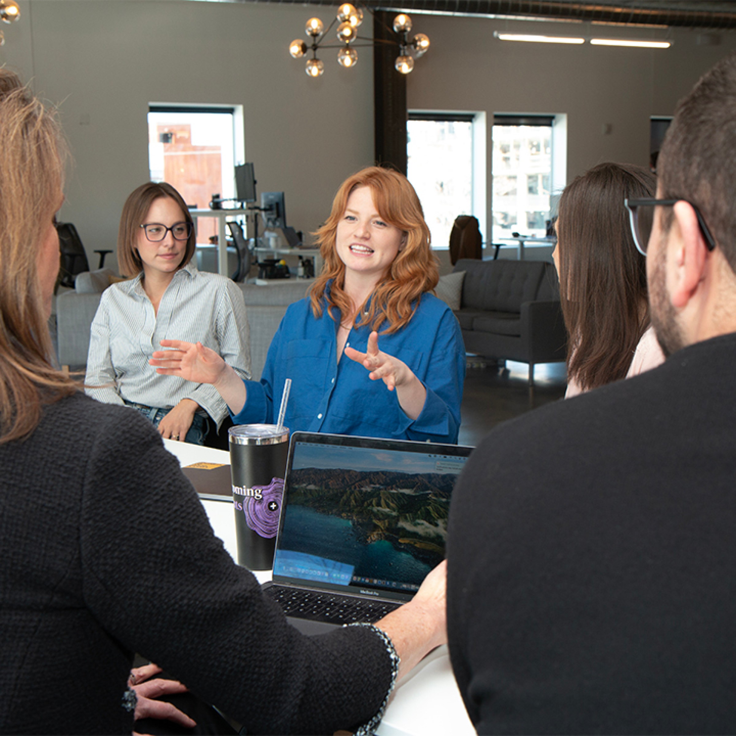 A group of people sitting at a table with a laptop