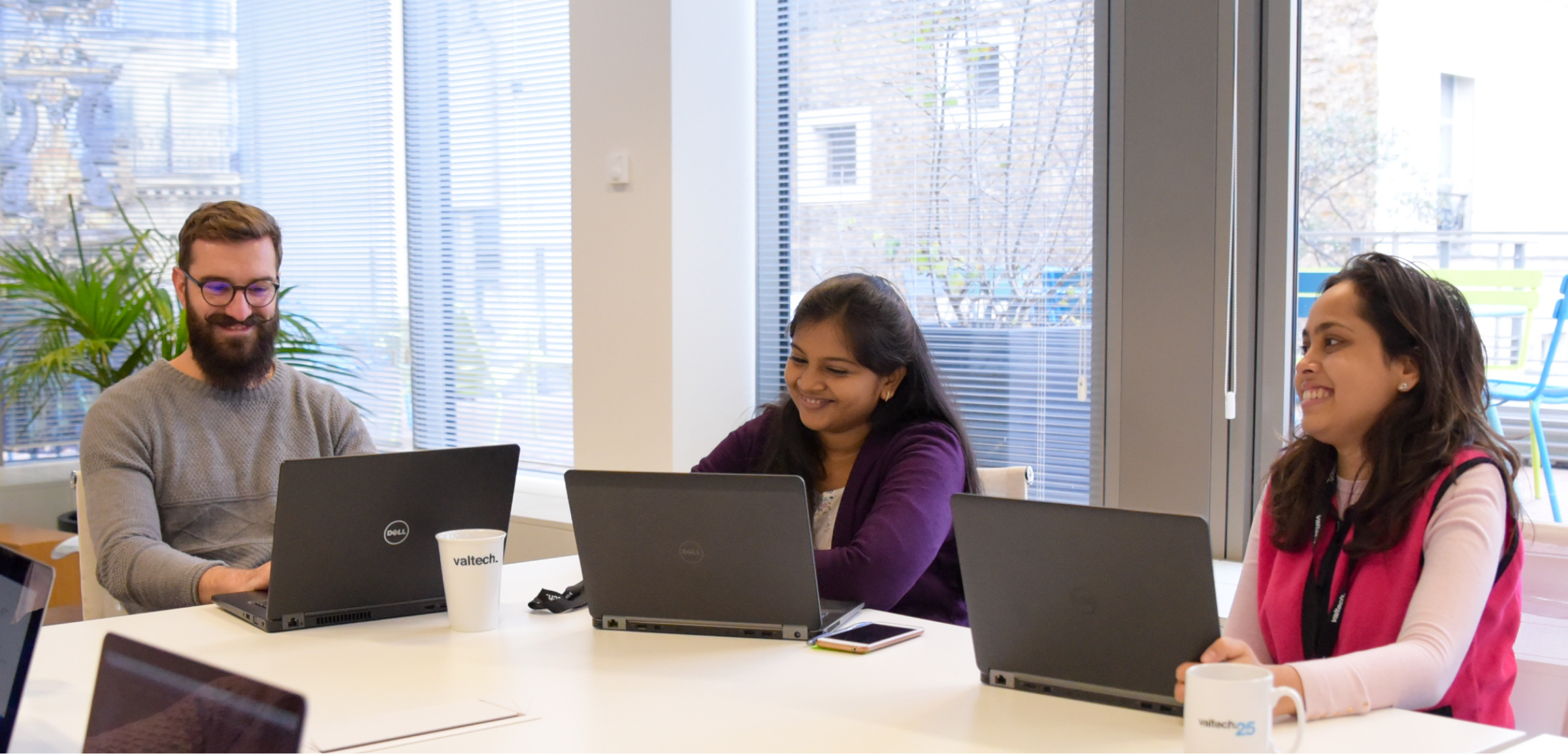 A woman and a man are sitting at a table with laptops