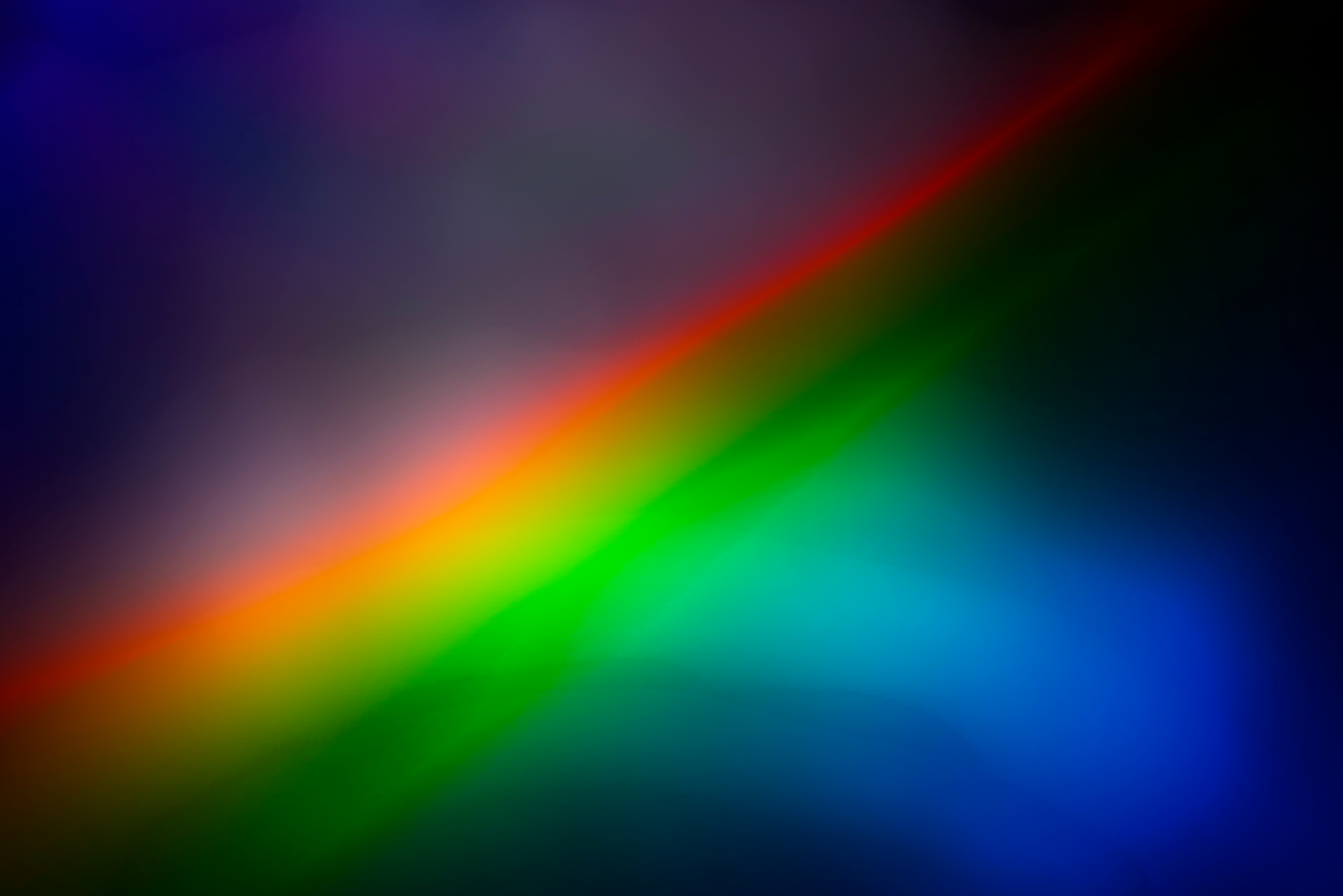 A vibrant abstract image featuring a diagonal gradient of bright colors resembling a rainbow light refraction effect.
