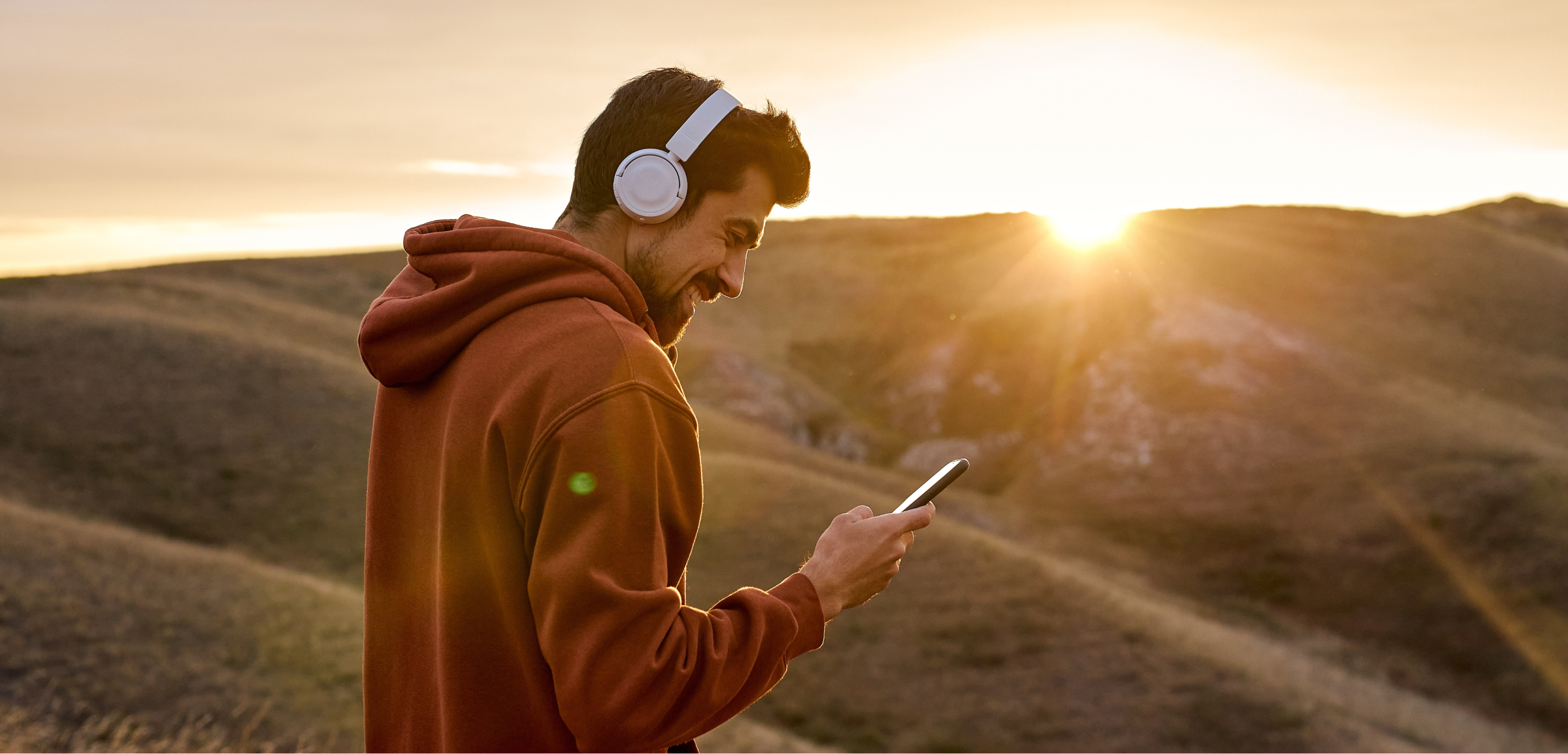 Transformative partnership man at sunset with headphones and smartphone Valtech